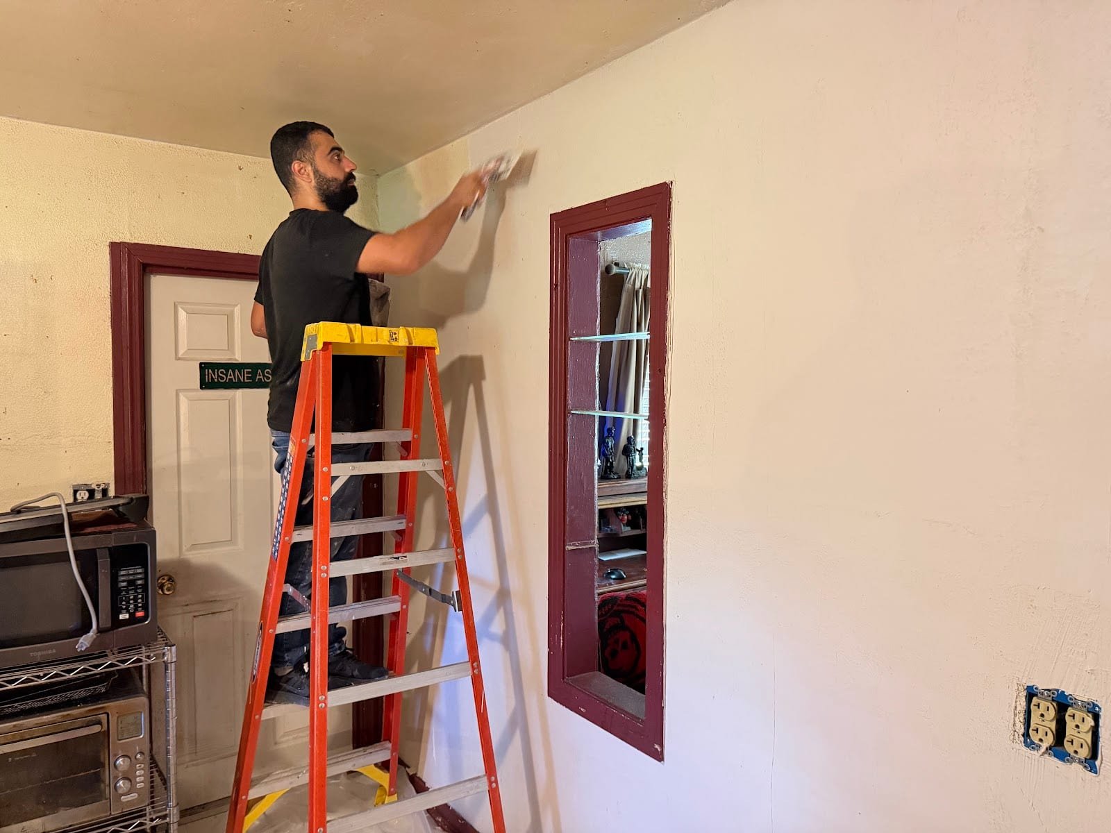 Licensed handyman finishing drywall compound on an interior wall in Tampa, FL