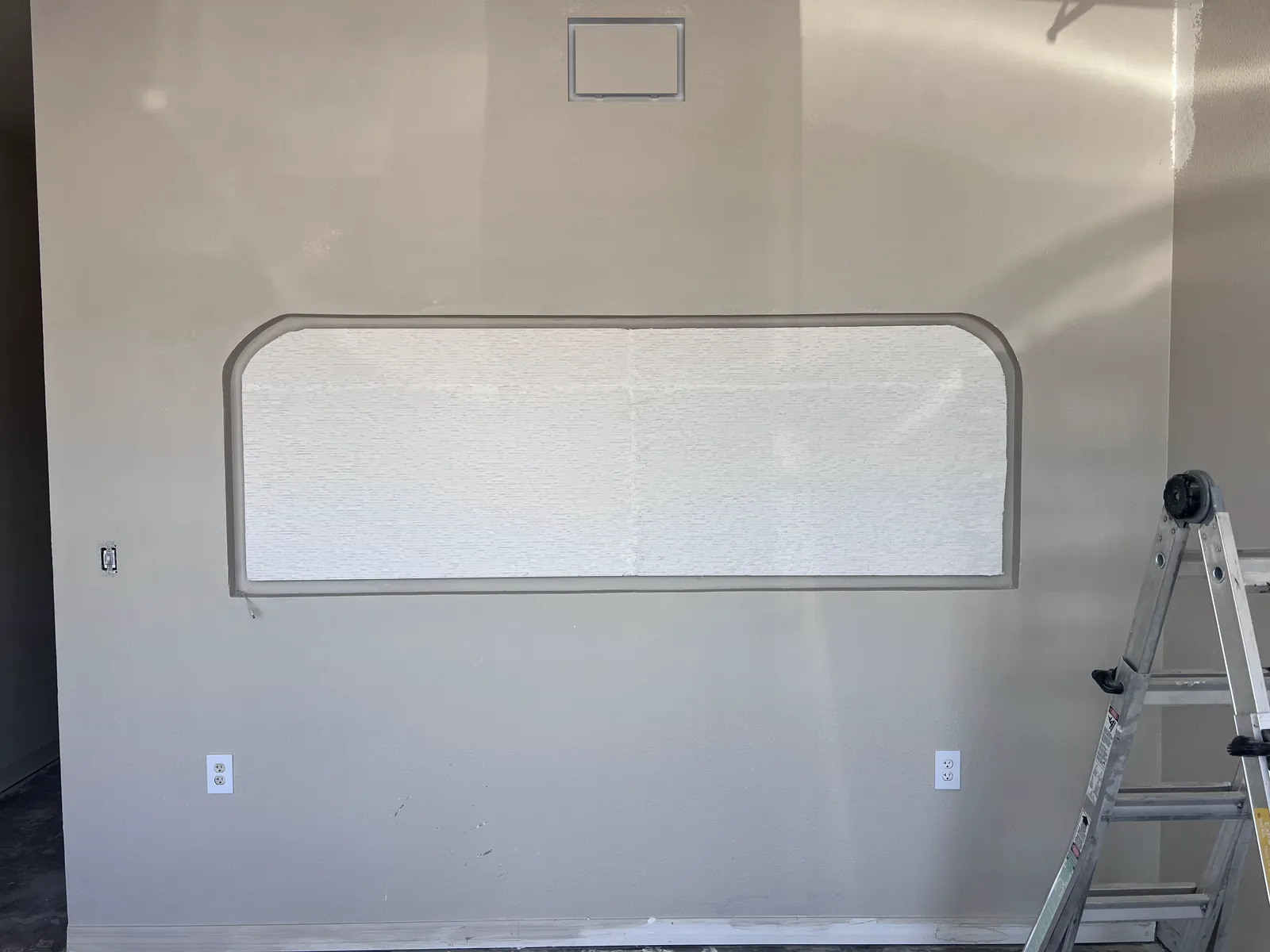 Drywall-finished wall with a rounded window opening and a ladder, Handyman Pros Florida