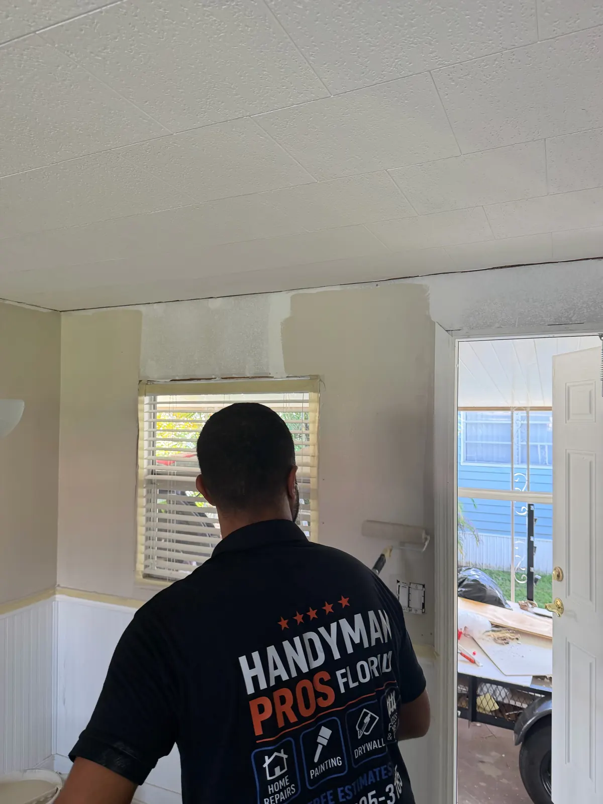 Handyman Pros Florida technician on an interior painting job in a room with white wainscoting in a Tampa Bay home