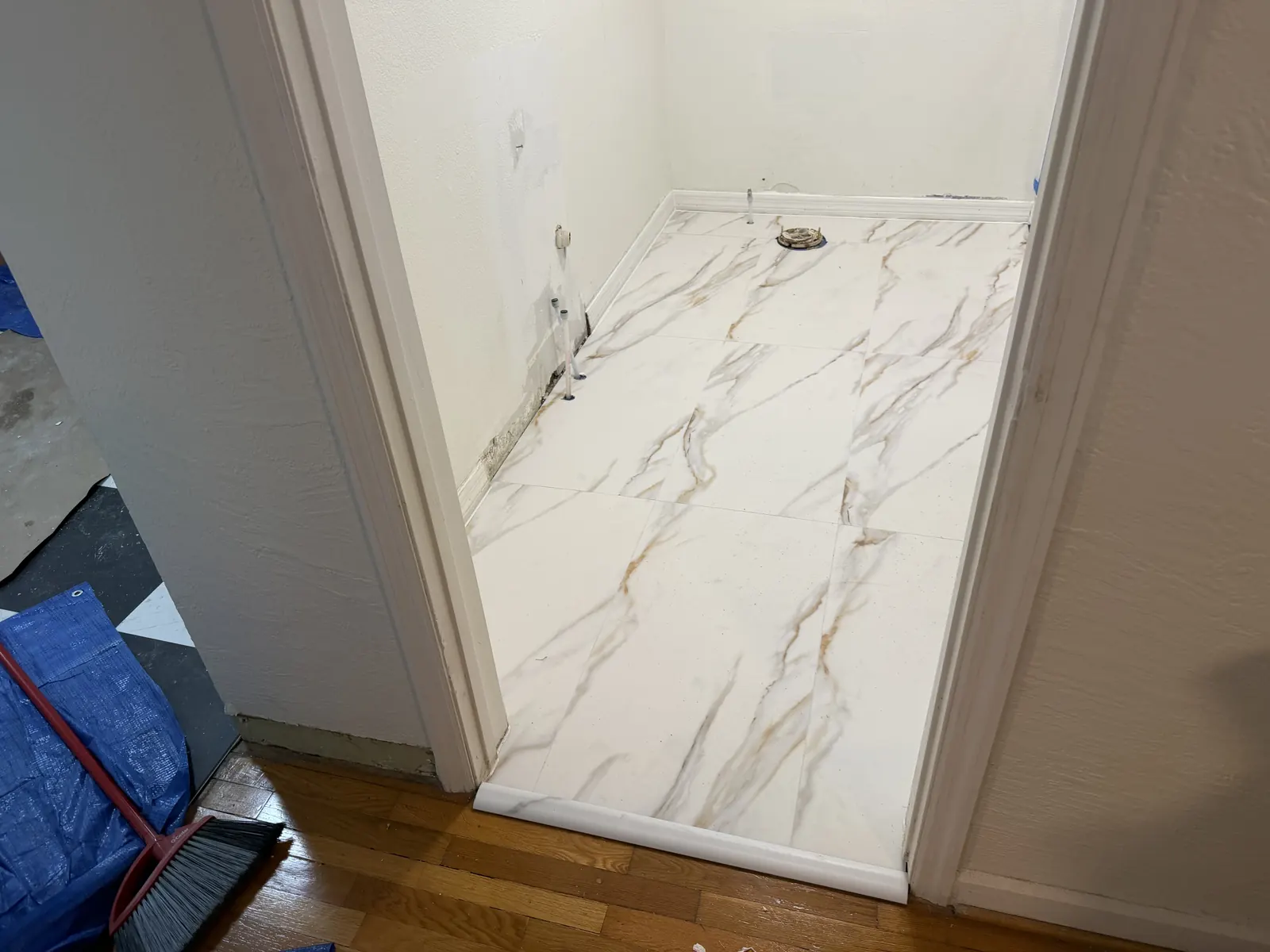 Marble-look floor tile installed in a small alcove with a floor drain in a Tampa Bay home, Handyman Pros Florida