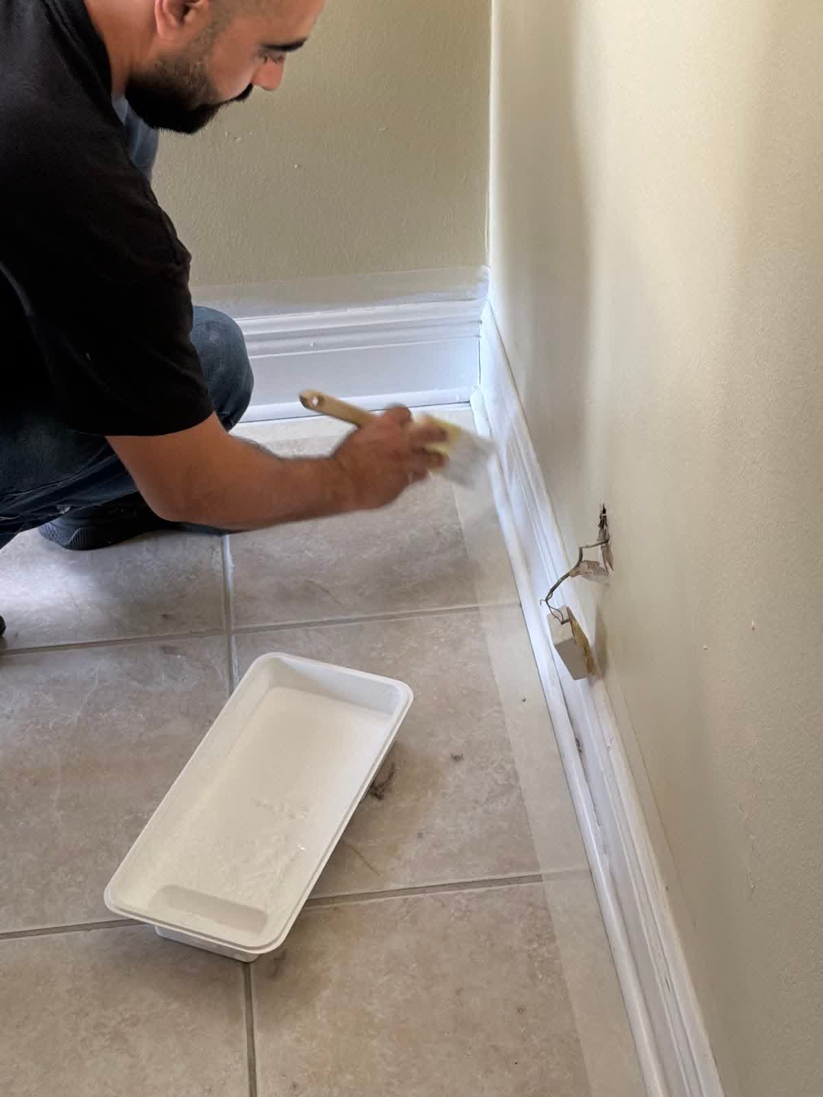 Handyman Pros FL crew member painting baseboard trim in a Tampa home