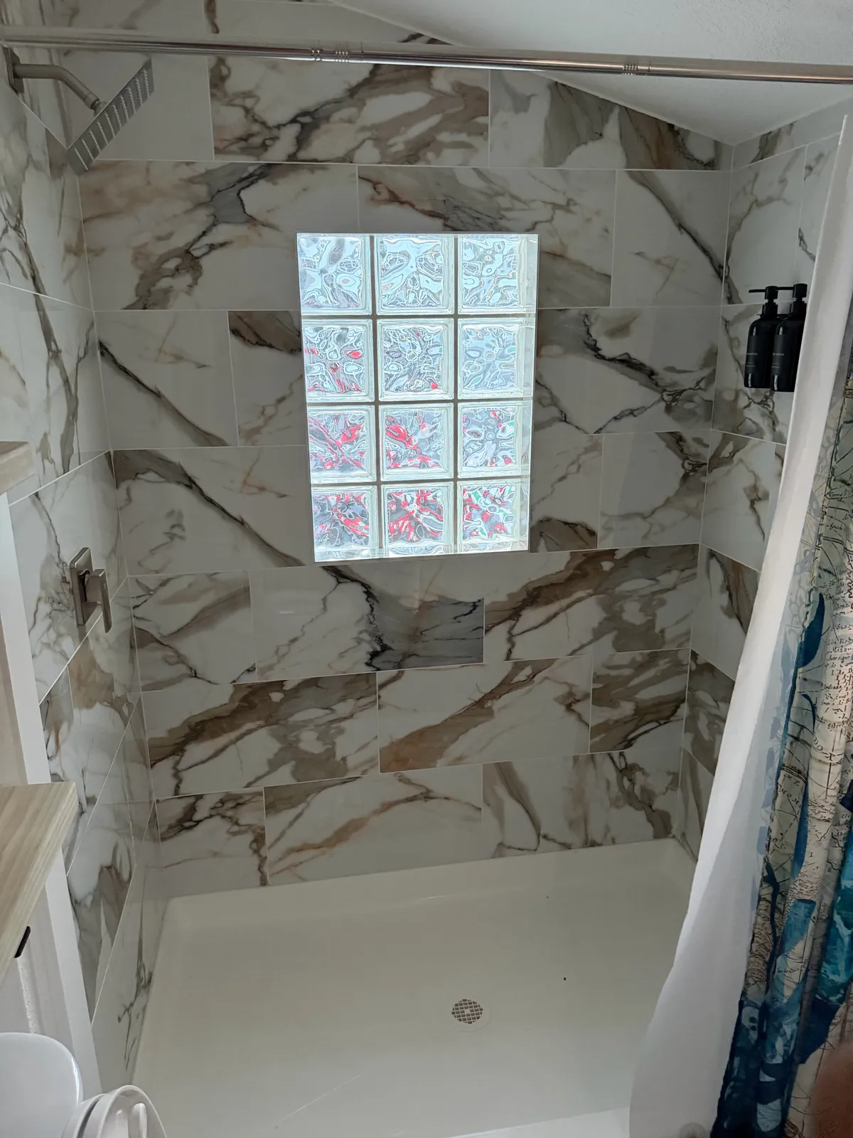 Marble tile shower with a glass block accent wall in a Tampa Bay bathroom